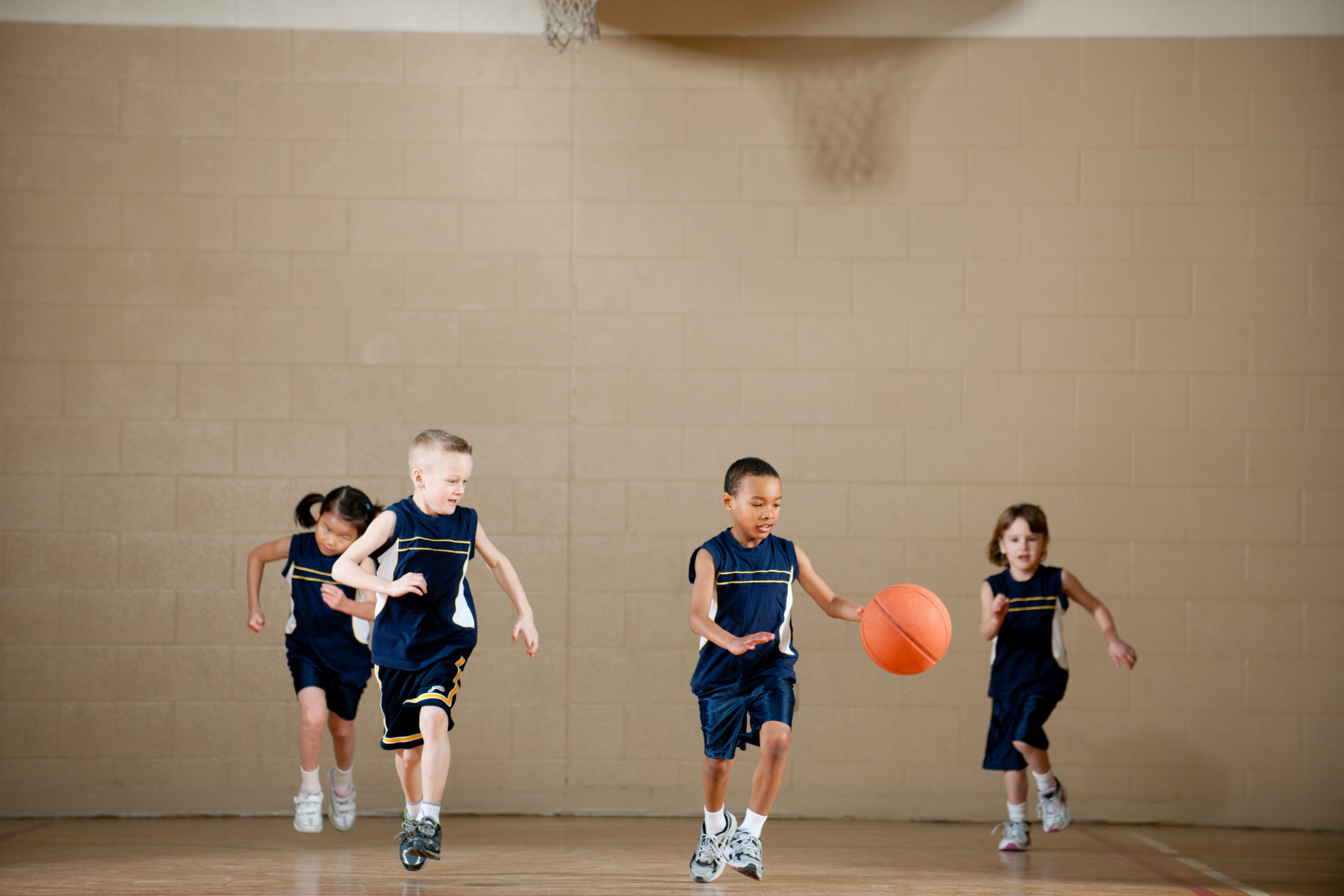 A diverse group of children playing basketball.