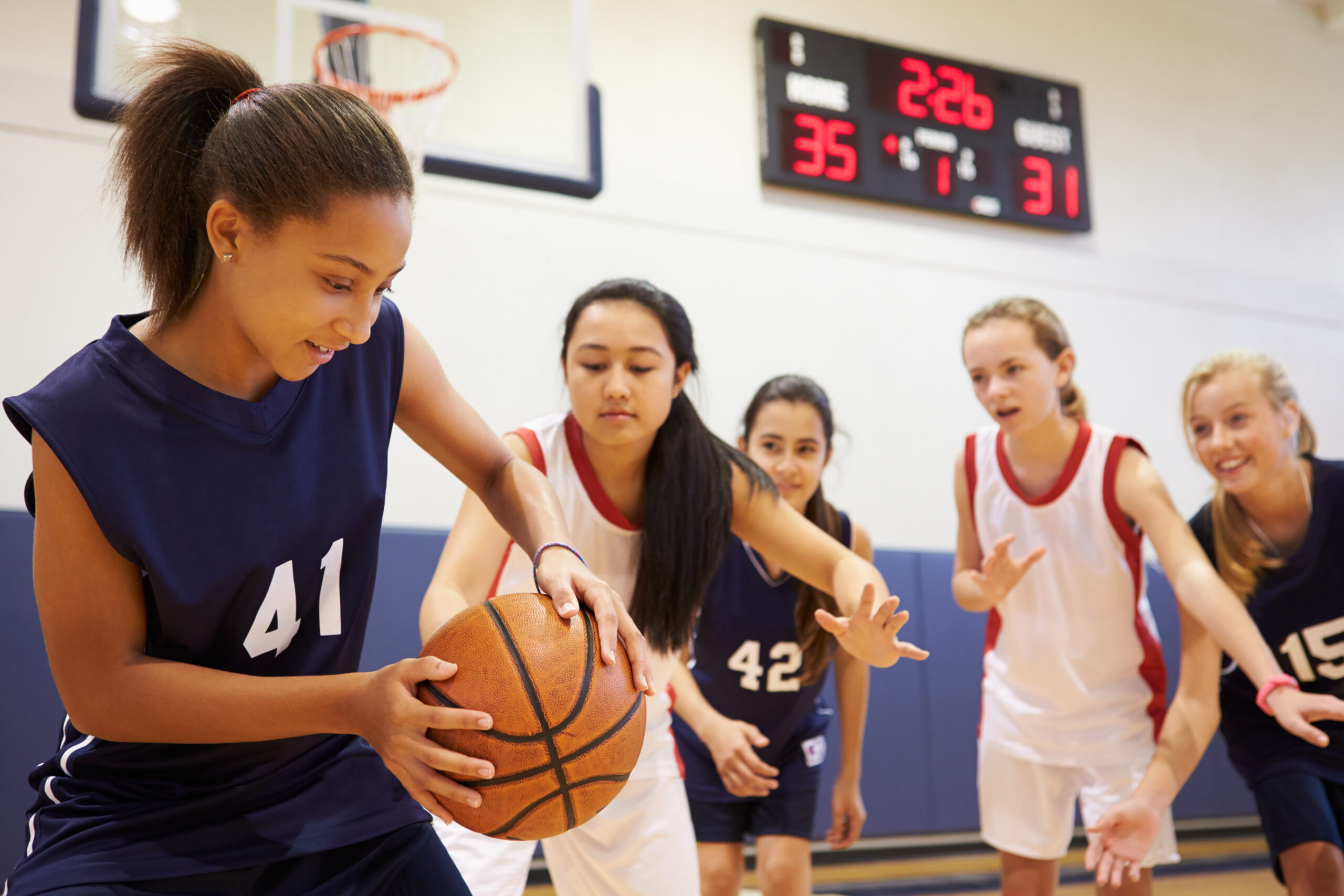 Female High School Basketball Team Playing Game In The Gym